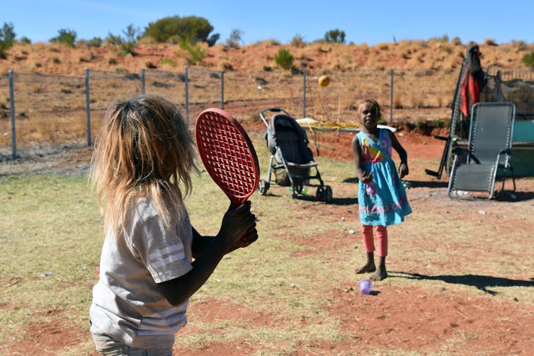 two children play ball game in desert scene