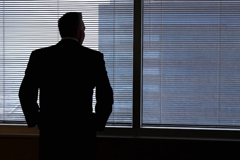 Homme d'affaires regardant par la fenêtre, pensif.