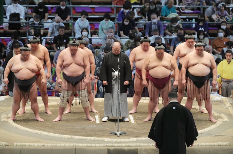 Sumo wrestlers and Japan Sumo Association chief Hakkaku (C) offer silent prayers for late former Japanese Prime Minister Shinzo Abe
