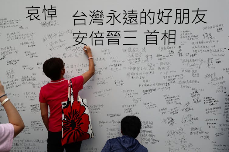 People write messages as they mourn the death of Japan's former Prime Minister Shinzo Abe in front of Japan-Taiwan Exchange Association office in Taipei,