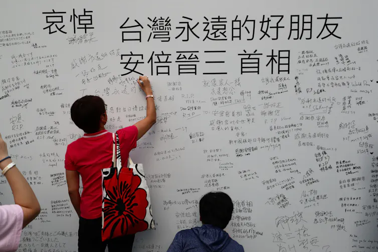 People write messages as they mourn the death of Japan's former Prime Minister Shinzo Abe in front of Japan-Taiwan Exchange Association office in Taipei,