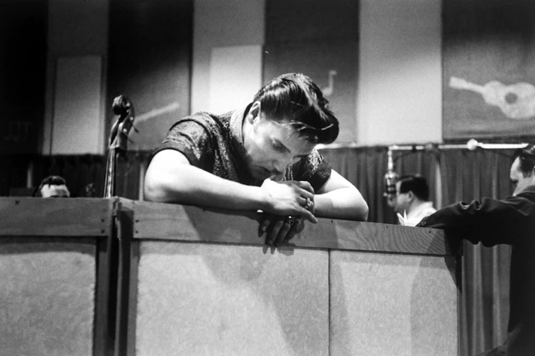Elvis Presley penché sur une barrière, il smeble perdu dans ses pensées.