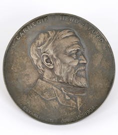 Gold medal with side profile of bearded man.