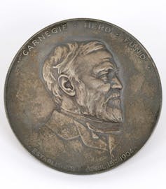 Gold medal with side profile of bearded man.