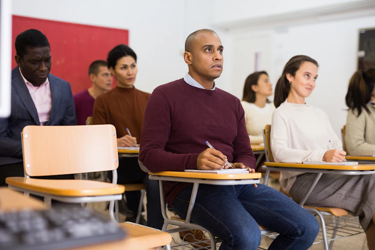 Des personnes assises dans une classe sont à l'écoute