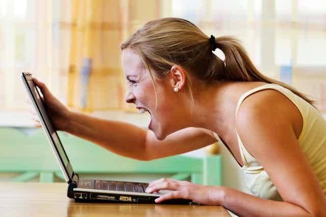 Angry woman screaming at laptop screen