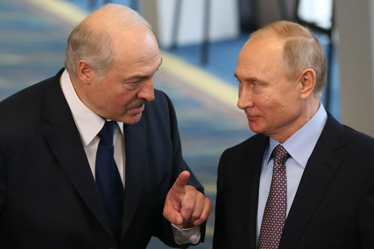 Two men in dark suits and ties, with one talking to the other.