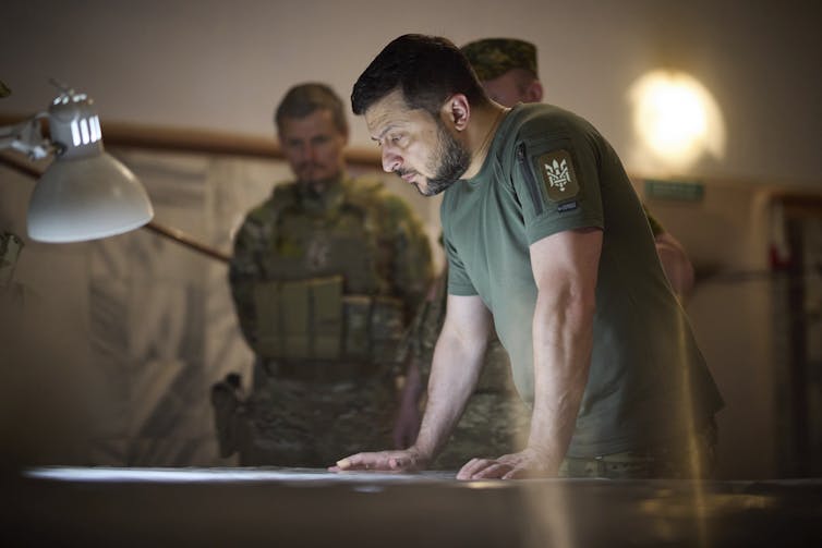 A man in a green shirt looking at something on a table.