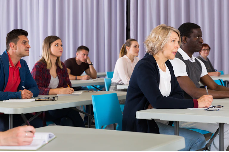 group of university students of different backgrounds and ages listen in class