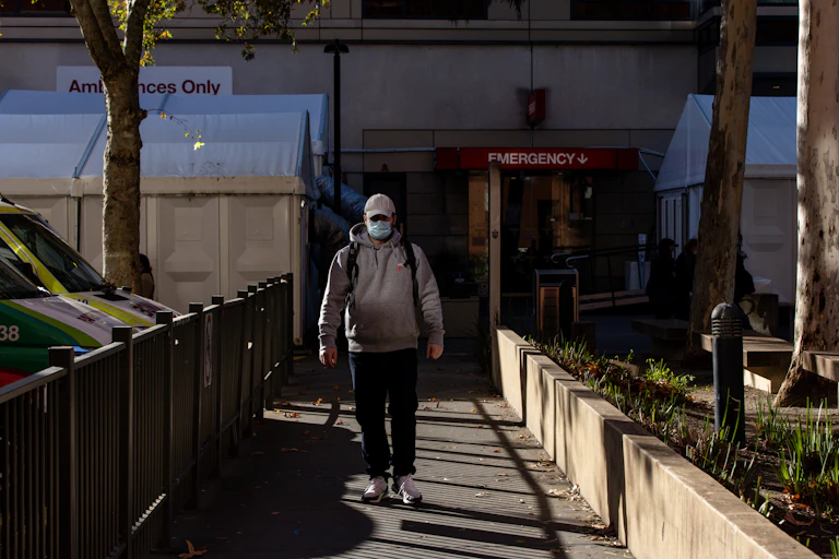 man walks out of hospital wearing mask