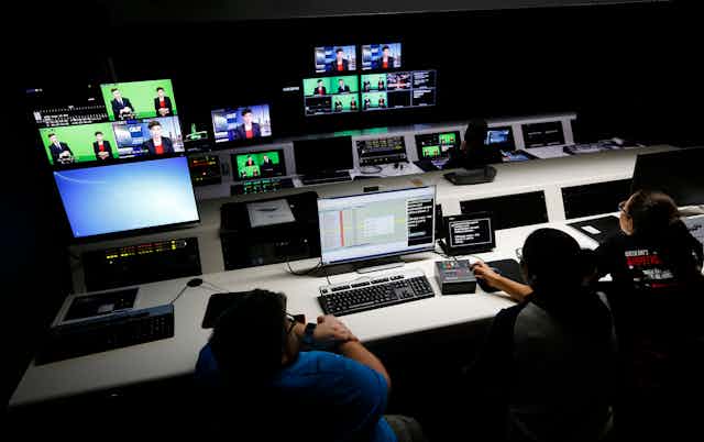 Journalism students interact with technology in a television control room on campus.