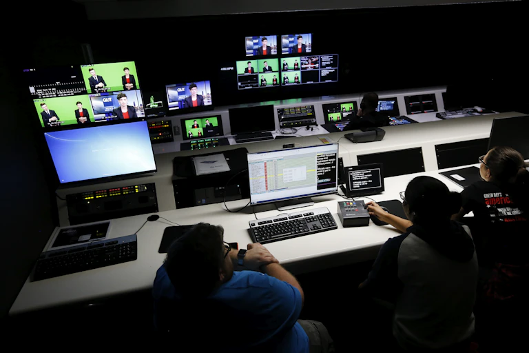 Journalism students interact with technology in a television control room on campus.