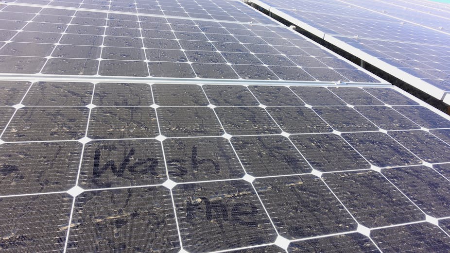 A dusty solar panel with 'wash me' written into it