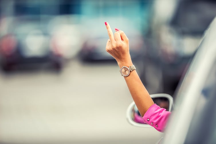 Driver gives the middle finger out of car window.