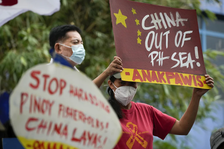 Two men wearing masks hold protest signs. One reads China Out of Ph Sea.