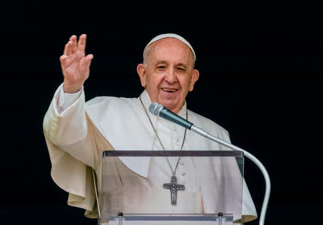 Le pape François, souriant, tend le bras