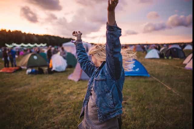 A girl dances in front of tents