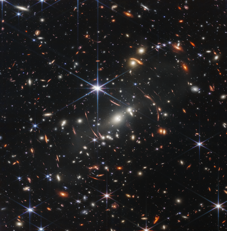 The background of space is black. Thousands of galaxies appear all across the view