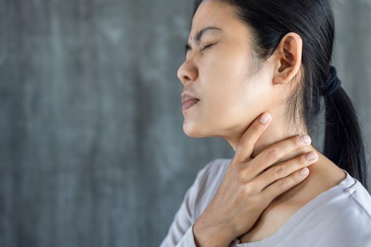 woman gestures to sore throat.