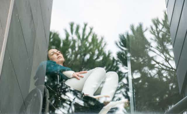 woman in wheelchair looks out window