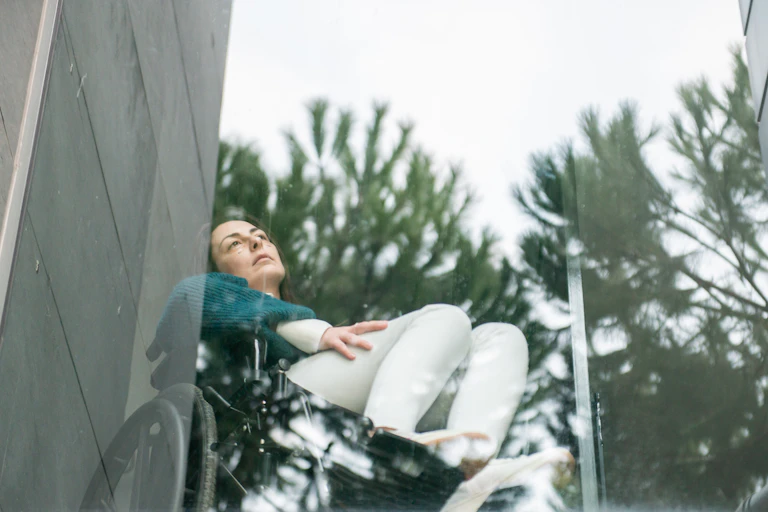 woman in wheelchair looks out window