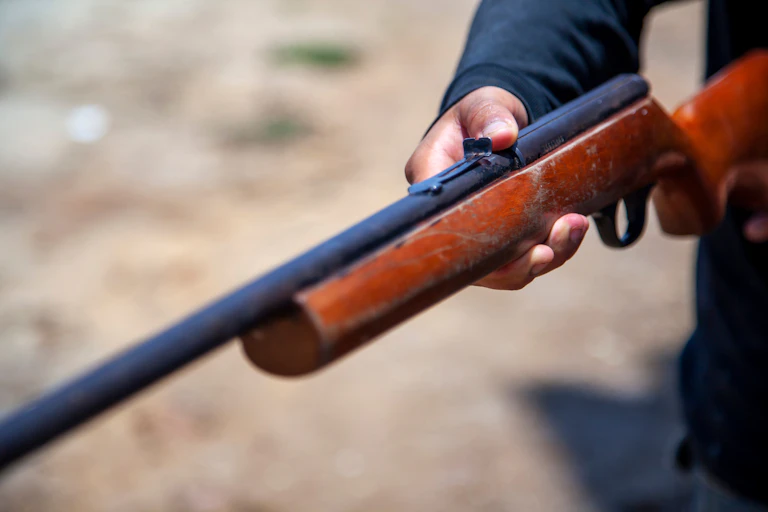 A hand holds out an old rifle.