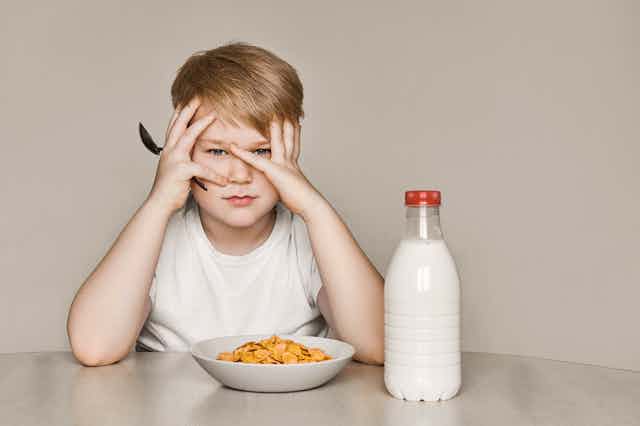 Boy looking bored with cereal bowl.
