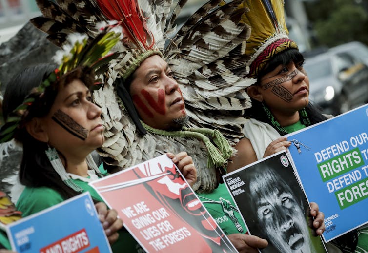 Indigenous Brazilian protesters holding signs.