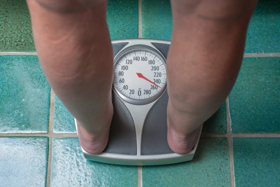 A person stands on a scale to measure their weight.