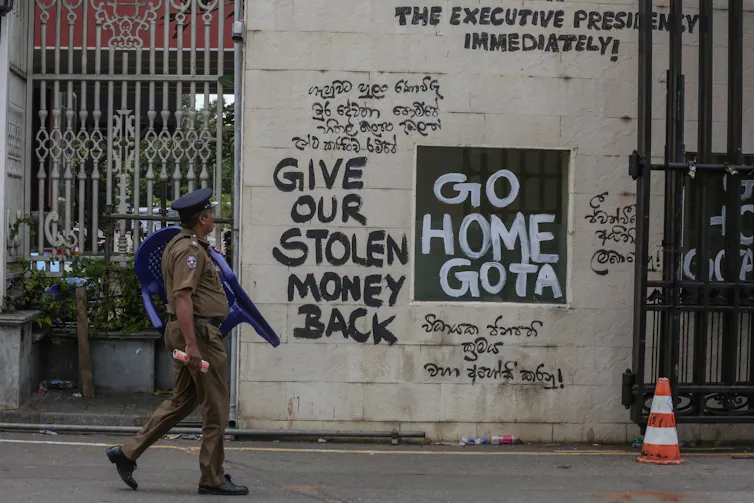Police officers walk past slogans written on the walls near the President's palace in Colombo, Sri Lanka,, July 12 2022.