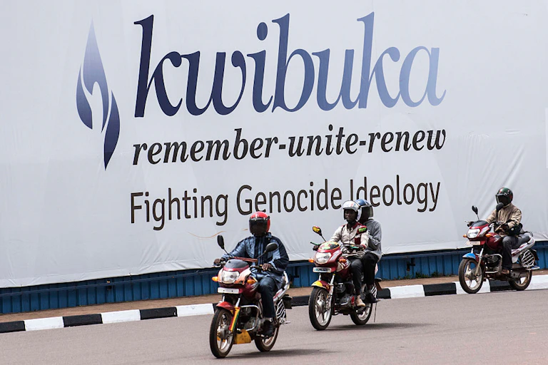 Motorcyclists riding past a billboard.