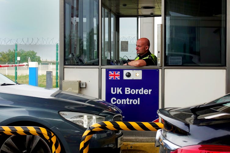 An officer sits in a UK Border Control booth as cars drive through the checkpoint in Calais