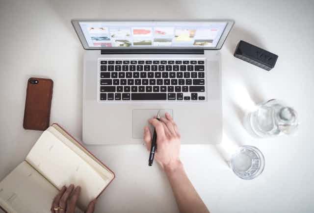 Table de travail avec ordinateur, smartphone en carnet en papier.