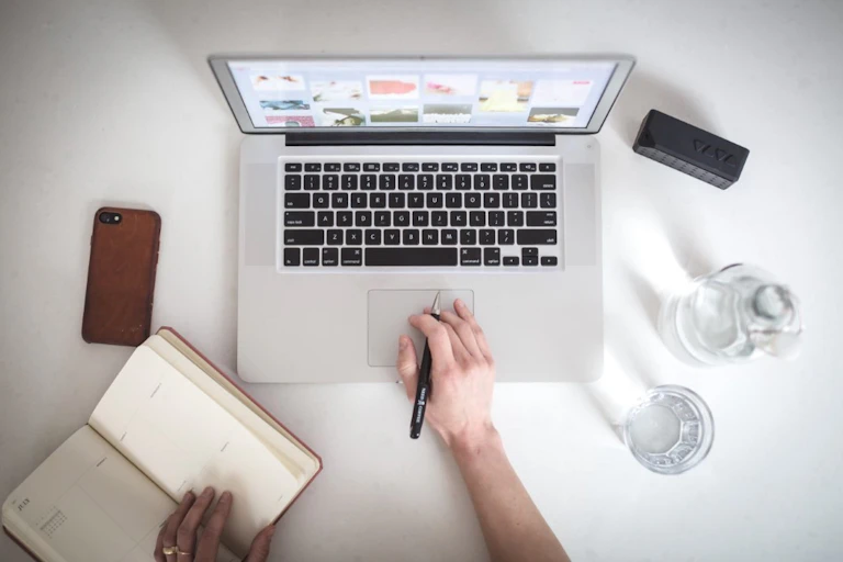 Table de travail avec ordinateur, smartphone en carnet en papier.