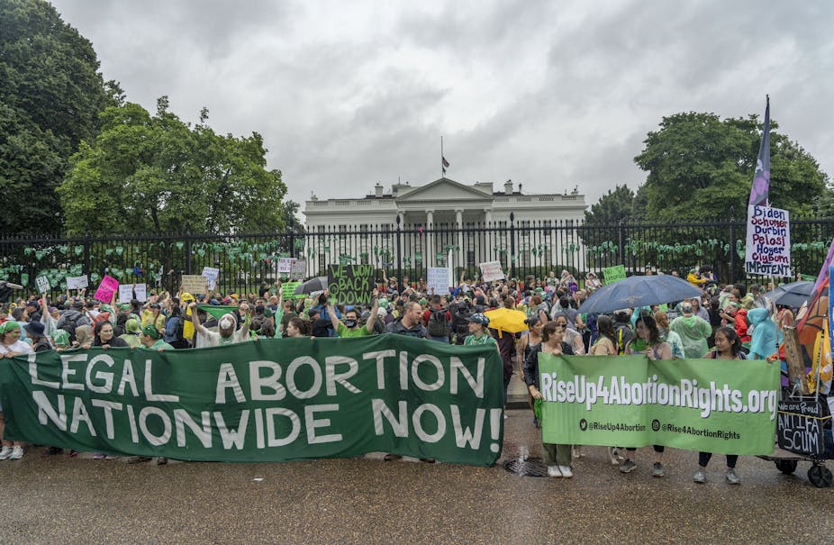 Protestors standing in front of the While House holding a banner that says, 'Legal Abortion Nationwide Now!'
