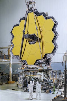 Un espejo dorado hexagonal gigante hecho de hexágonos dorados, en un laboratorio.
