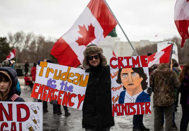 Demonstrators hold up anti-Justin Trudeau signs and Canadian flags