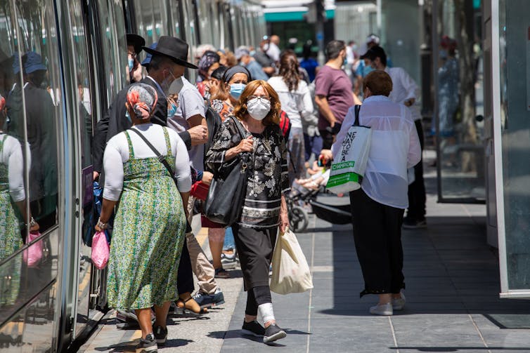 Israelis in masks get on and off a train