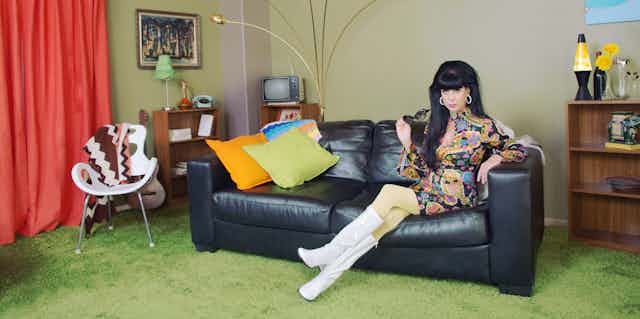 Woman in 1970s fashion sits on sofa