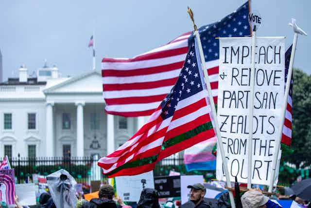 "Impeach and remove partisan zealots from the court," reads one protester's sign in front of a large white building.