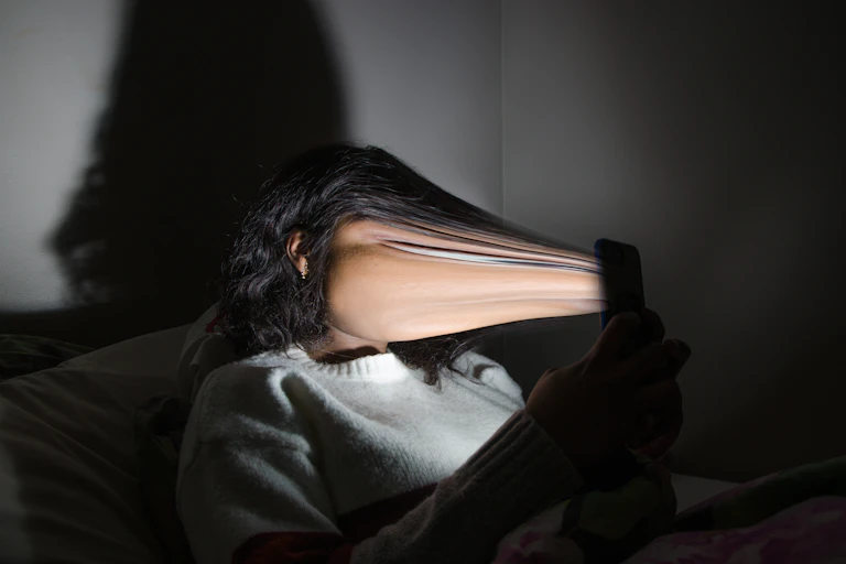 Rendering of woman's face being sucked into a smartphone screen.