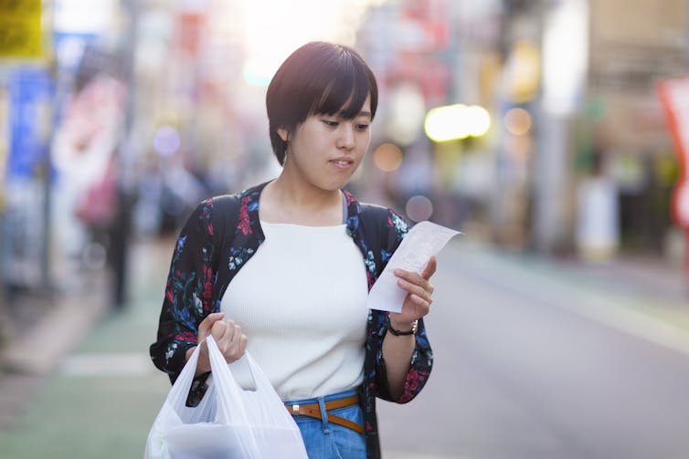 Young woman looking at a grocery receipt.