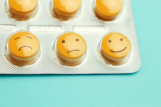 Pills with a sad face, neutral face and happy face
