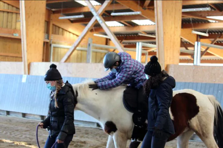 Un jeune patient, à cheval, se penche sur l’encolure de sa monture