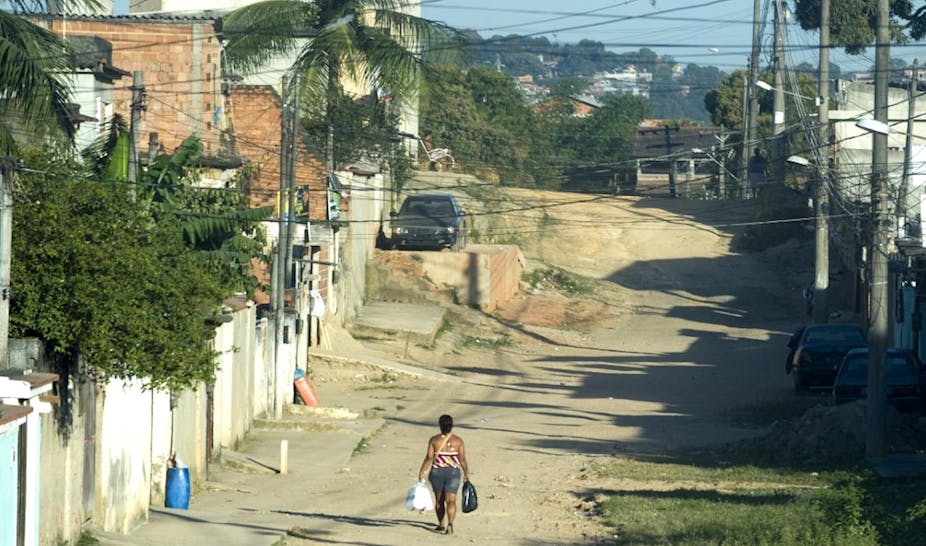 Une femme marche le long d'une rue en terre battue dans la zone suburbaine de Rio de Janeiro, au Brésil, une ville qui se caractérise par de fortes inégalités sociales.