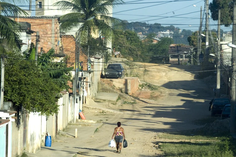 Une femme marche le long d'une rue en terre battue dans la zone suburbaine de Rio de Janeiro, au Brésil, une ville qui se caractérise par de fortes inégalités sociales.