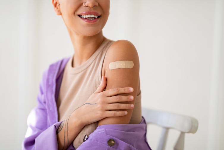 A smiling young woman with a bandaid on her arm.