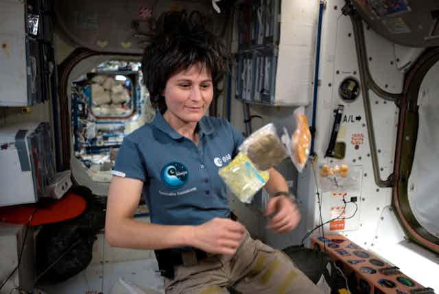 L'astronaute Samantha Cristoforetti flotte dans l'ISS devant trois sachets de nourriture