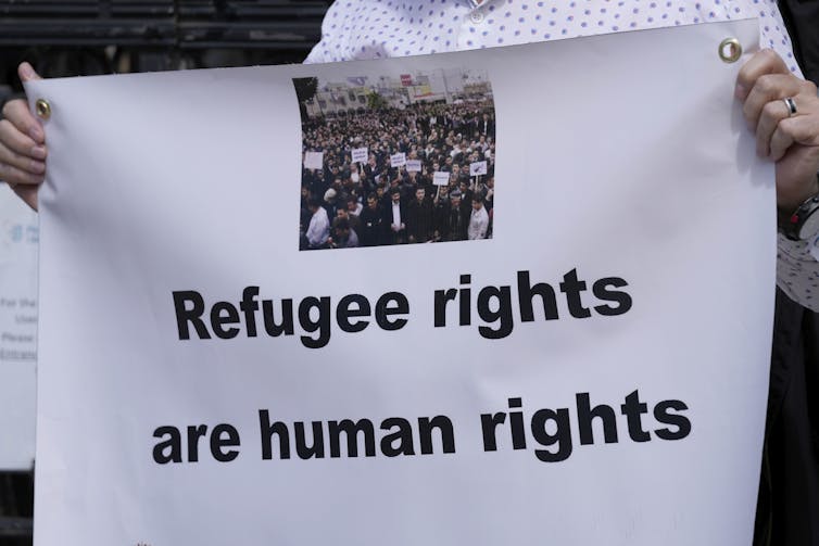 Someone holding a sign that says 'Refugee rights are human rights'