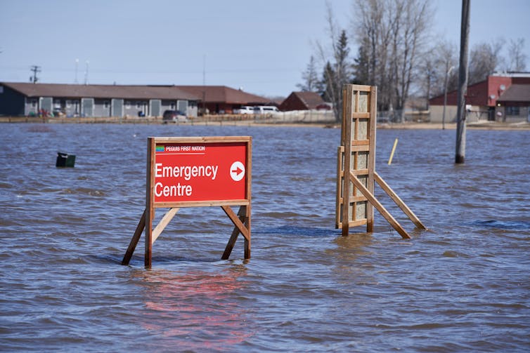 An emergency sign is seen above rising flood waters.